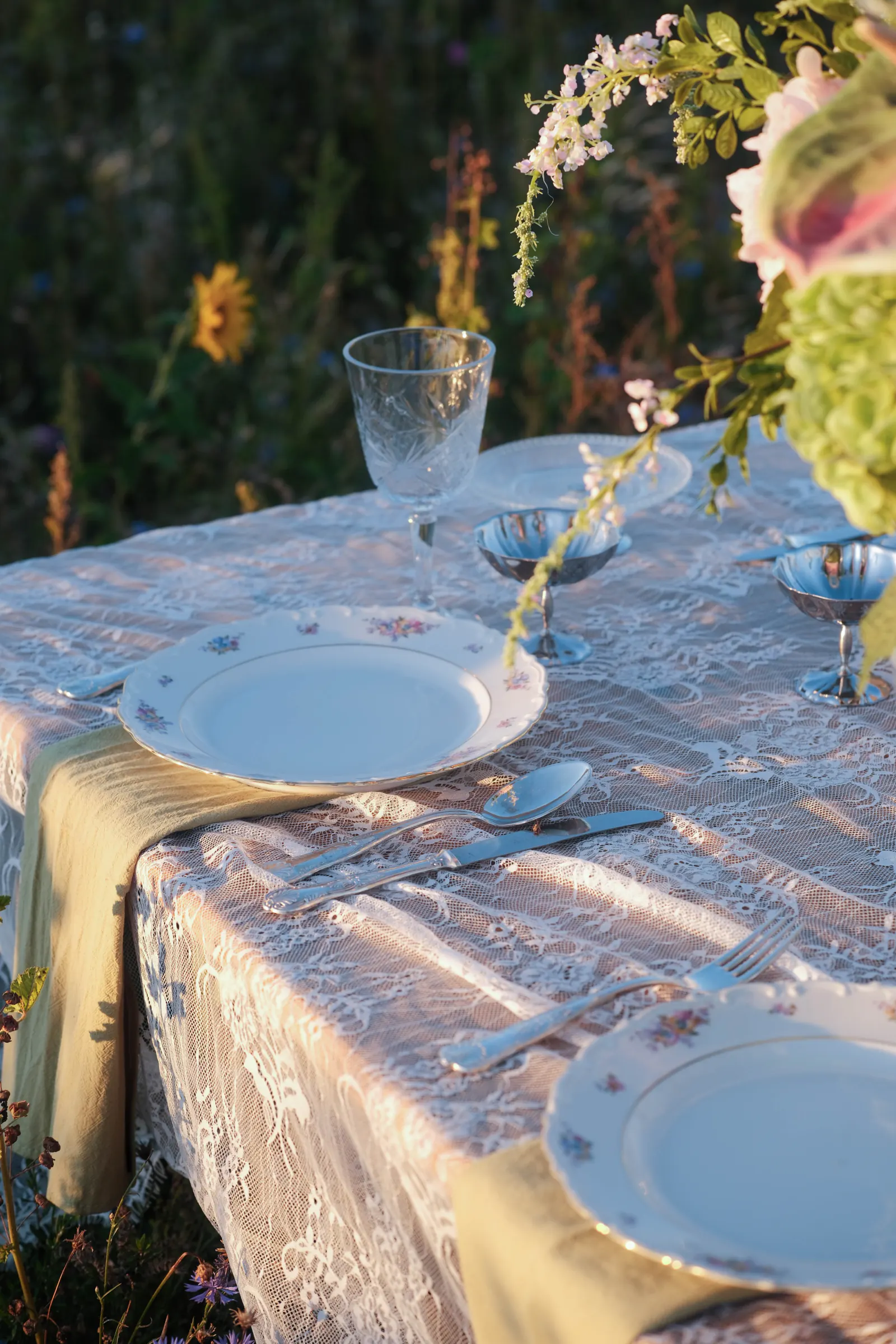 Gedekte dinertafel met vintage servies, bloemen en kanten tafellinnen